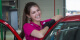 Image of a member of the GO Rentals team wearing a pink shirt smiling as she prepares a rental car for a customer