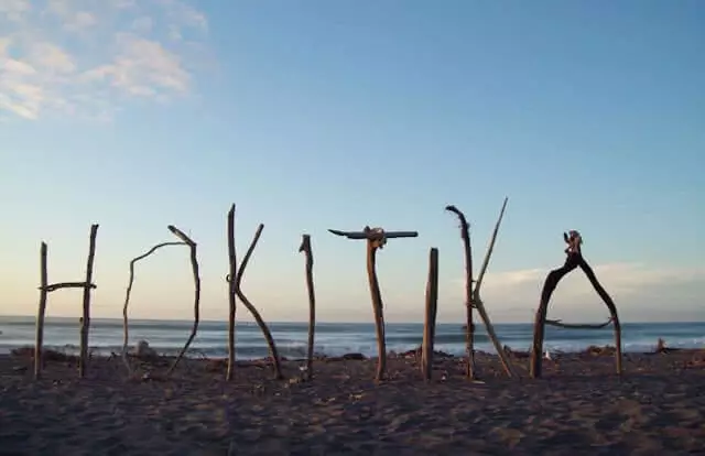 Image of the word Hokitika spelt out in sticks on the beach at Hokitika