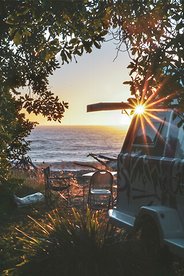 Image of a GO Glamper trailer parked next to a beach at sunset