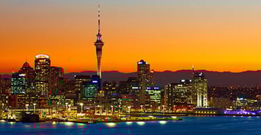 Image of the Auckland city skyline taken at sunset with the lights shining on all the buildings and in the port