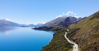Image of a lake, mountains and road in the background with a car in the foreground