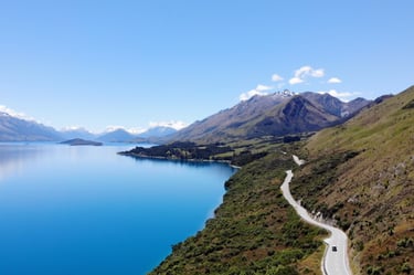 Image of a lake, mountains and road in the background with a car in the foreground
