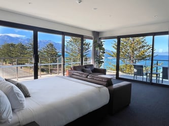 Spacious hotel room with large windows, ocean view, and mountain backdrop