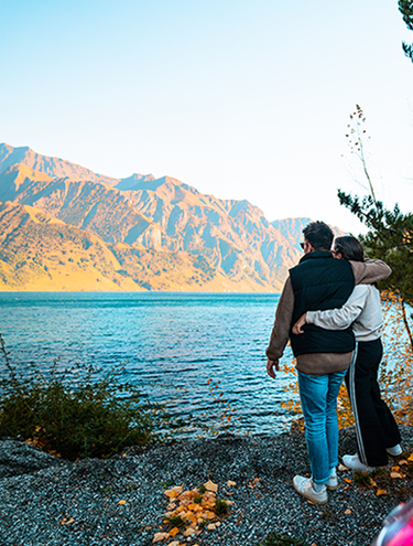 Image of a couple standing outside their GO Rentals vehicle and admiring New Zealand's Mountain and lake landscape