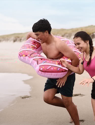 A boy and a girl are running into the sea for summer