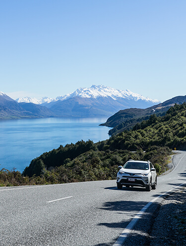 Image of a white Toyota Rav4 driving around Lake Wakatipu near Queenstown on a sunny day
