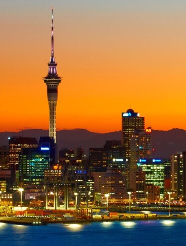Image of the Auckland city skyline taken at sunset with the lights shining on all the buildings and in the port