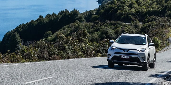 Image of a white Toyota Rav4 driving around Lake Wakatipu near Queenstown on a sunny day