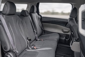 Interior image of a Kia Carnival Hybrid showing the middle row of seats and the walkway to the back seats