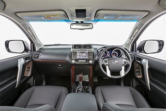 Interior image of the front of a Toyota Land Cruiser Prado 4x4 rental car showing the dashboard and entertainment system