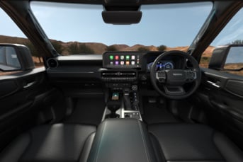 Interior image of the front of a Toyota Land Cruiser Prado Hybrid 4x4 rental car showing the dashboard and entertainment system
