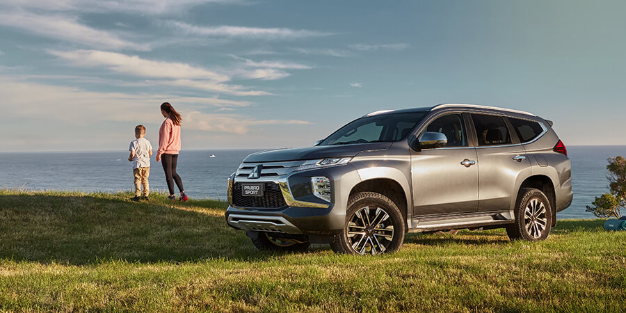 Exterior image of a grey Hyundai Santa Fe parked off-road with snow-capped mountains in the background