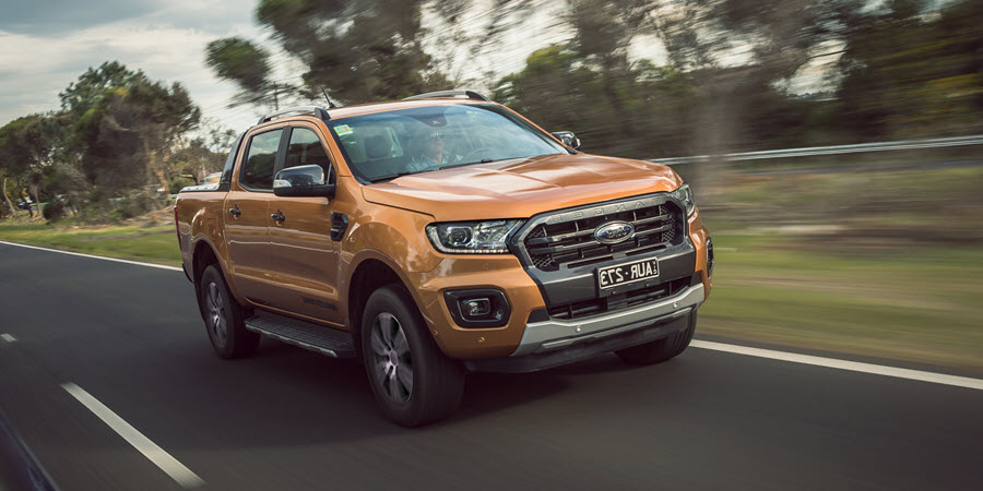 Exterior Image of a red Toyota Hilux 4x4 parked at a builders yard with piles of wood in background