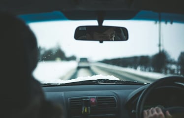 View from inside a car of a snowy road through a foggy windshield