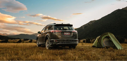 GO Rentals cal in the field, next to a tent with the mountains in the background.
