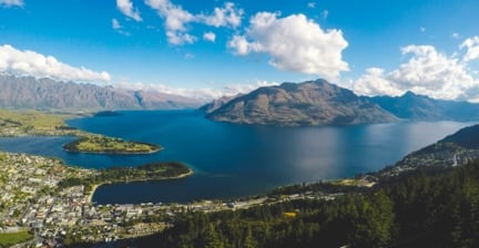 Panoramic view of a lake surrounded by mountains and a town below