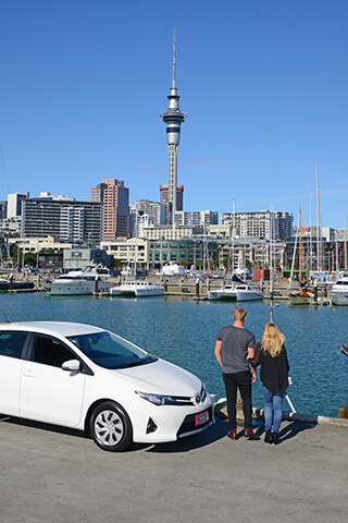 Image of a white Toyota Corolla parked up at the viaduct in Auckland overlooking the Skytower