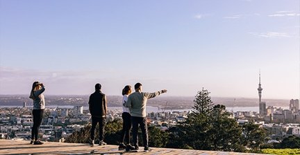 People enjoying a view of Auckland city and Sky Tower from a hilltop
