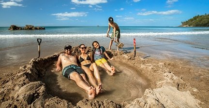 People relaxing in a hot pool dug into the sand at Hot Water Beach