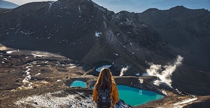 Hiker looking at emerald lakes and volcanic mountains on the Tongariro Alpine Crossing