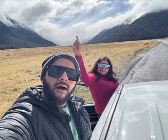 Couple taking a selfie from a car with a mountain valley in the background