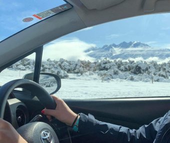 Driving through a snowy landscape with mountains in the background