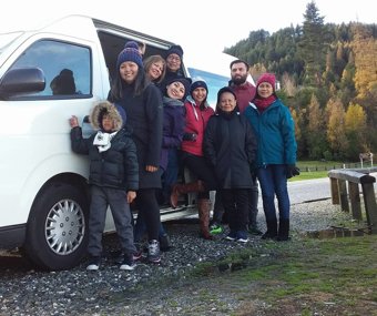Group of people posing beside a white van in a scenic outdoor setting