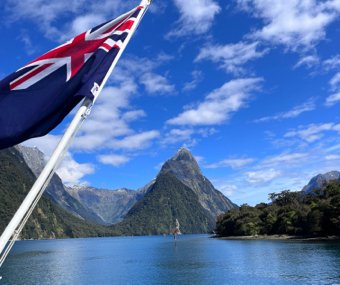 New Zealand flag waving in front of a mountain and lake
