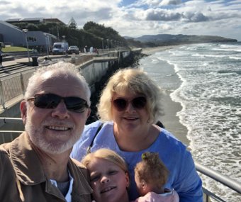 Image of Julie with her family beside the ocean beach
