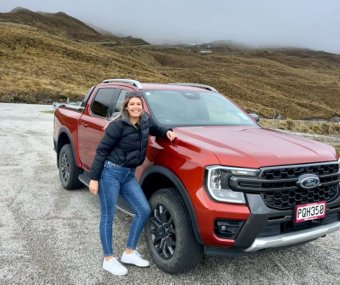 Woman posing next to a red Ford pickup truck on a foggy mountain road