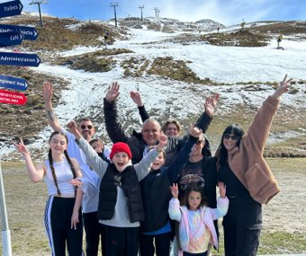 Excited group posing at a ski resort with snowy slopes