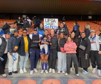 Group of people smiling and posing at a stadium