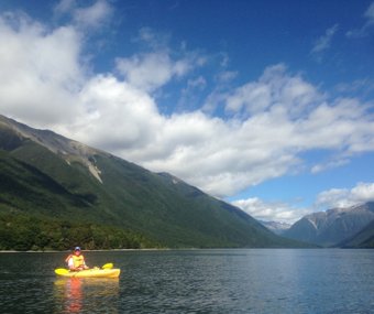 Person kayaking on a mountain lake under a blue sky