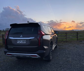 SUV parked at sunset near a rural fence