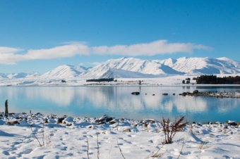 Snow-covered lake with mountain reflections under a clear blue sky