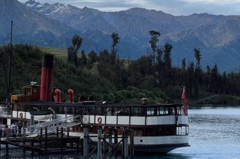 Vintage steamship docked on Lake Wakatipu with mountains in the background