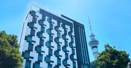 Sudima Auckland City hotel building with Sky Tower in the background
