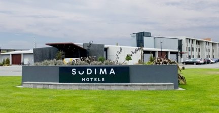 Sign and exterior of Sudima Christchurch Airport hotel with green lawn