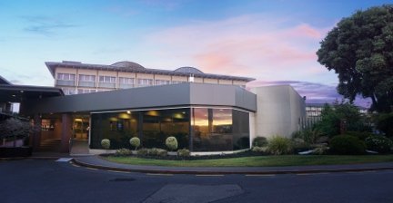 Sudima Rotorua hotel at sunset with curved glass-front building
