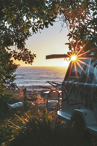 Image of a GO Glamper trailer parked next to a beach at sunset