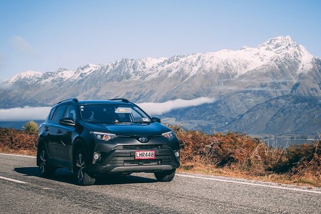 Popup image of a Toyota Rav4 with GO Rentals pink plates driving on a South Island road with mountains in the background