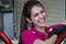 Image of a member of the GO Rentals team wearing a pink shirt smiling as she prepares a rental car for a customer