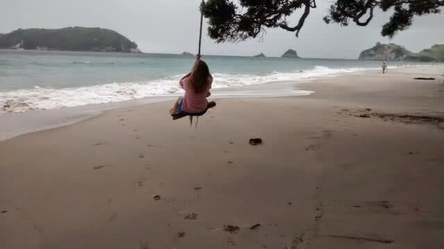 Image of someone swinging on the rope swing on Hahei Beach, Coromandel Peninsula