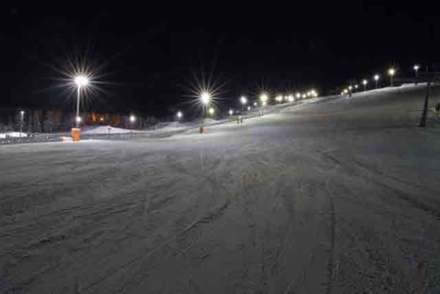 Image of a slope on Coronet Peak lit up for night skiing