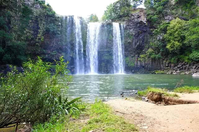 A water fall flowing down a cliff face in 3 streams into the lagoon below.