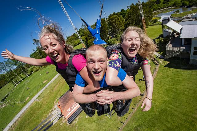 two women and a man riding a giant bungy swing