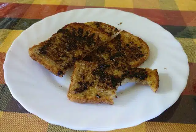 Two slices of vogels toast with marmite on them