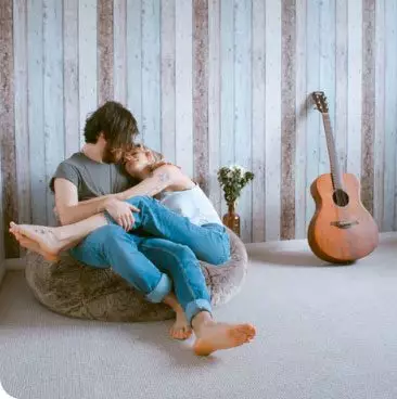 A couple sat together on a bean bag with a guitar in shot