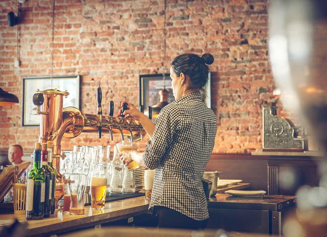 Image of a female bartender pouring a beer