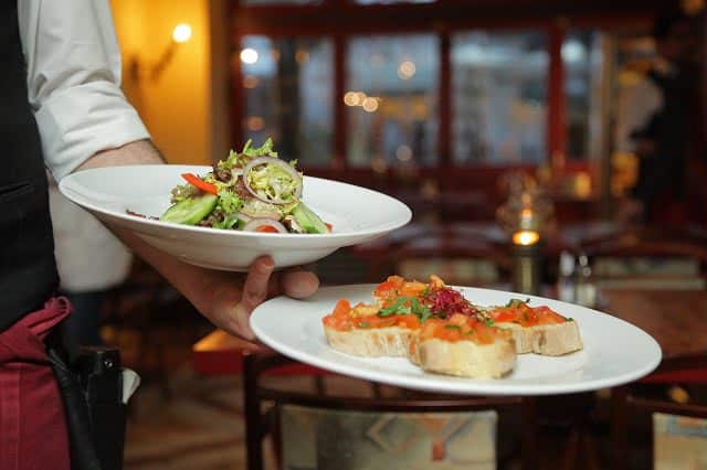 Image of a waiter serving food to a table